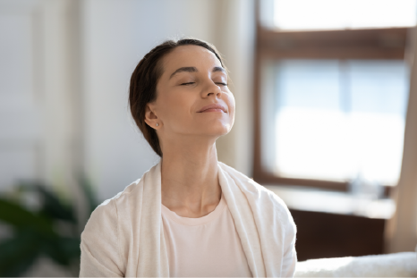 Women breathing fresh cool air because of working conditioner, giving face to sunlight from window | Advanced Heating and Air Conditioning